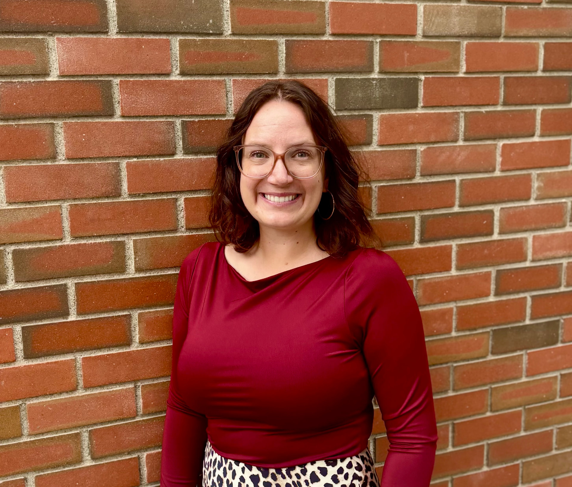Katelyn Wilson, clinician and owner of Low Tide Counseling, smiling in front of a brick wall
