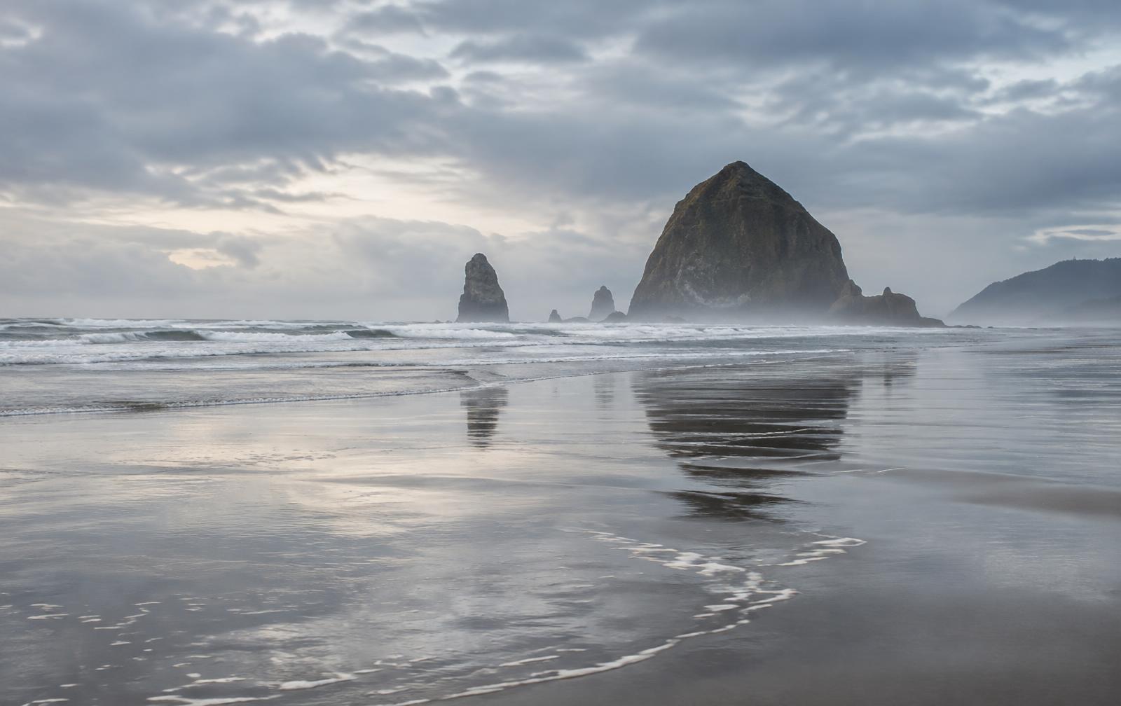 Low tide at Cannon Beach, with Haystack Rock reflected in wet sand