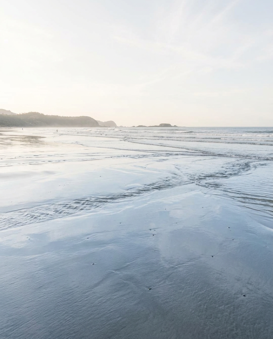 Gentle ocean tides receding over wet sand at low tide