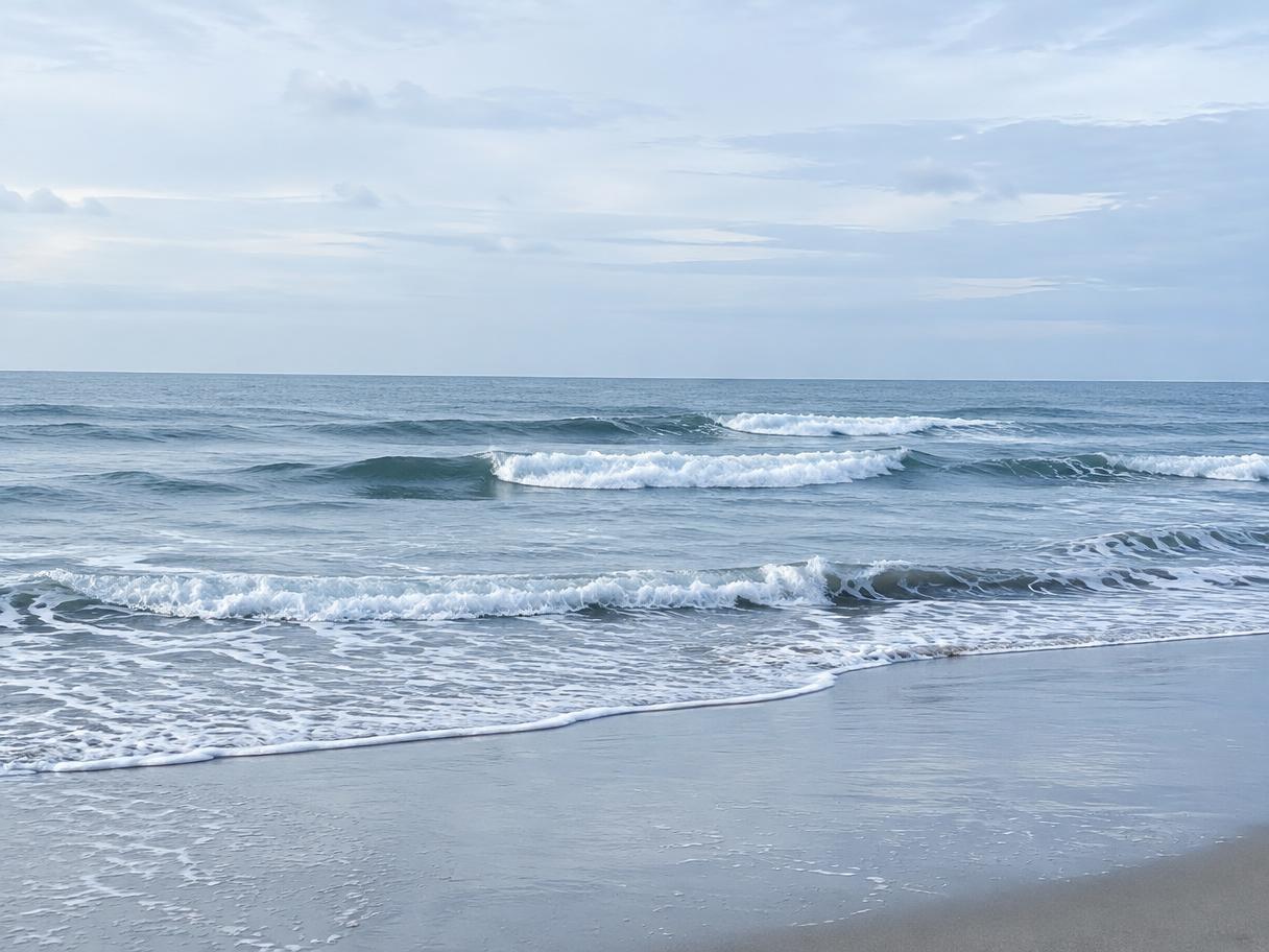 Gentle waves rolling toward shore under a soft blue sky